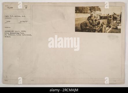 Soldiers working together to assemble a Q.M.C. truck at the Motor Assembling Park in St. Nazaire, Loire Inferieure, France. This photograph was taken by Capt. P.D. Miller in 1918 during World War I. The soldiers are seen carefully putting together the truck's various components. Stock Photo