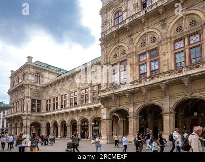 Vienna, AT – June 9, 2023 Three quarter view of tourists walking by the historic 1,709-seat Renaissance Revival Vienna Operahouse. The first major bui Stock Photo
