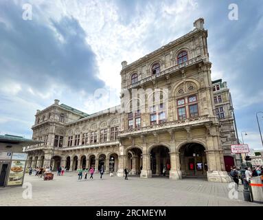 Vienna, AT – June 9, 2023 Tourists walking by the historic 1,709-seat Renaissance Revival Vienna Operahouse. Built in 1869, it was the first major bui Stock Photo