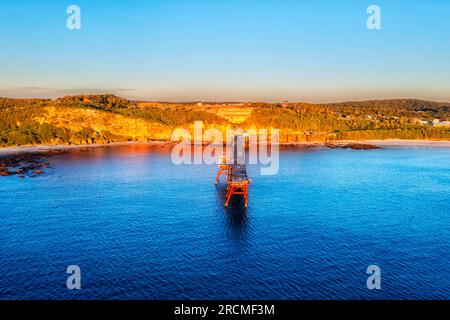 Long historic jetty at Middle Camp beach of Catherine hill bay coastal town in Australia - aerial sunrise landscape. Stock Photo