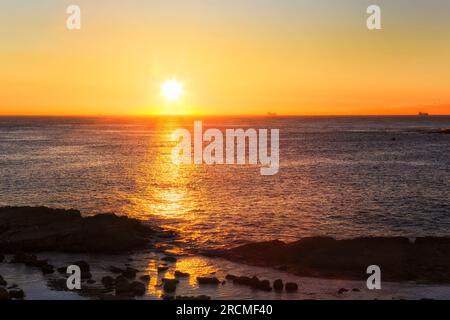 Scenic rising sun over Pacific ocean horizon of Swansea head cliffs in Australia. Stock Photo