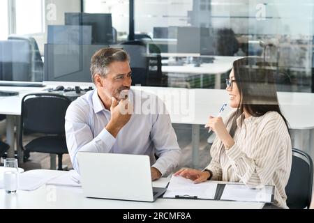 Two happy diverse professional executives working in office with laptop. Stock Photo