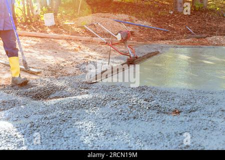 Worker on building site are leveling concrete for driveway with slump concrete trowel Stock Photo