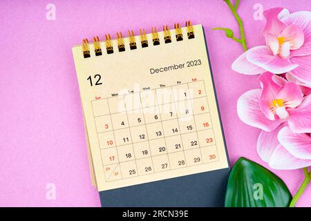 December 2023 calendar desk and pink orchid on pink background. Stock Photo