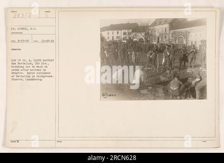 Soldiers from Company A, 119th Machine Gun Battalion, 32nd Division, breaking ice to wash in a creek upon their arrival in Ernster. Motor equipment of the Battalion can be seen in the background. This photo was taken on November 22, 1918, by Lt. Dowell during World War I. Stock Photo