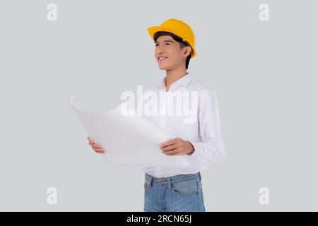 Portrait young asian man is engineer wearing helmet holding and looking blueprint with confident isolated on white background, handsome male is archit Stock Photo