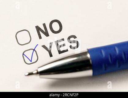 Check boxes yes or no on white paper. checkbox YES. marked with tick mark and blue pen on white paper background. Vote Yes. answer choice Yes. vote fo Stock Photo
