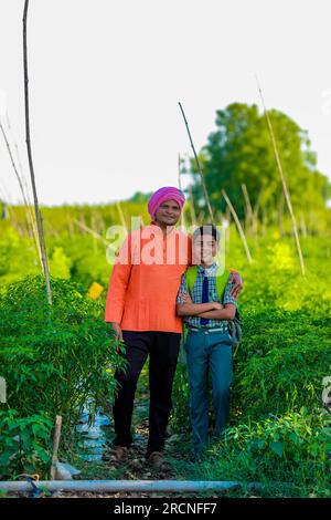 Cute indian farmer child in school uniform with his father at agriculture field, happy father and son Stock Photo