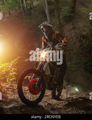 Motorcyclist on a sport motorcycle rides through a difficult forest area Stock Photo