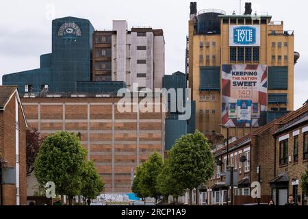 Tate and Lyle sugar factory in Silvertown (Newham) East London. View from residential street with houses and trees in foreground. England, UK. Stock Photo