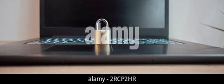 Wide view image of a golden padlock placed on an open laptop computer. Conceptual image of cyber security, data protection and firewall. Stock Photo