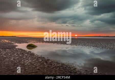 Moody dramatic skies and sunset reflections over Bowness on Solway Cumbria north east England UK Stock Photo