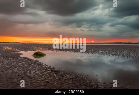 Moody dramatic skies and sunset reflections over Bowness on Solway Cumbria north east England UK Stock Photo