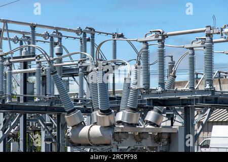 Close up view of some high-voltage bushings on a utility transformer at an electrical substation which allows an electrical conductor to pass safely t Stock Photo