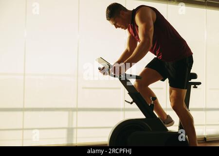 Young Caucasian man pushing himself to new limits on his state-of-the-art exercise bike, using the latest in fitness technology to achieve his health Stock Photo