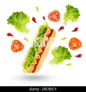 Flying ingredients for classic hot dog isolated on white background. Levitating wheat bun, sausage, tomatoes and fresh salad lettuce leaves. Fast food Stock Photo