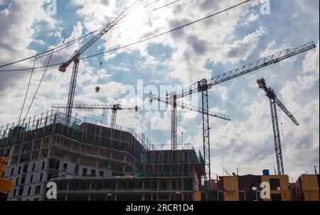 Cranes working at residential building. Cloudy blue sky Stock Photo