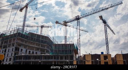Cranes working at residential building. Cloudy blue sky Stock Photo