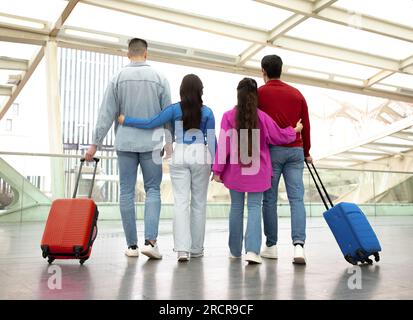 Back View Of Two Couples Standing With Suitcases In Airport Stock Photo