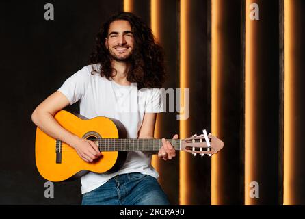 Happy Musician Man Holding And Playing Acoustic Guitar In Studio Stock Photo