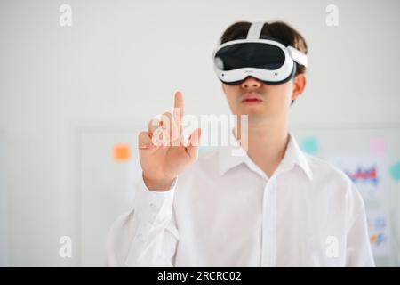 Businessman wearing virtual reality goggles headset and touching AI world, Happy man touching digital pixel screen in modern office, Futuristic Stock Photo