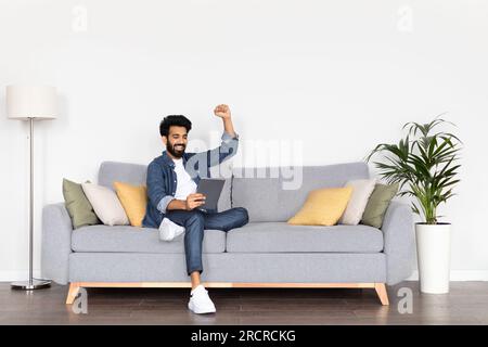 Happy arab man using digital tablet and gesturing at home Stock Photo
