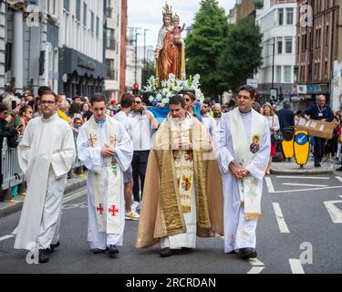 London, UK.  16 July 2023.  Priests ahead of people carrying the statue of Our Lady of Mount Carmel past St Peter's Italian Church during the Procession of Our Lady of Mount Carmel, starting at St Peter's Italian Church and then around the streets of Clerkenwell.  Floats carry life size depictions of Biblical scenes in a Roman Catholic festival which has taken place annually since the 1880s in the area which was once the capital's Little Italy. Credit: Stephen Chung / Alamy Live News Stock Photo