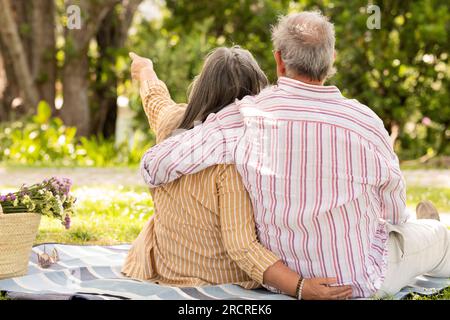 Happy senor european man and lady sit on plaid, enjoy romantic date, picnic Stock Photo