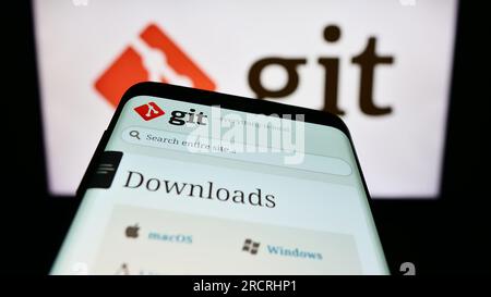 Smartphone with webiste of distributed version control system Git on screen in front of logo. Focus on top-left of phone display. Stock Photo