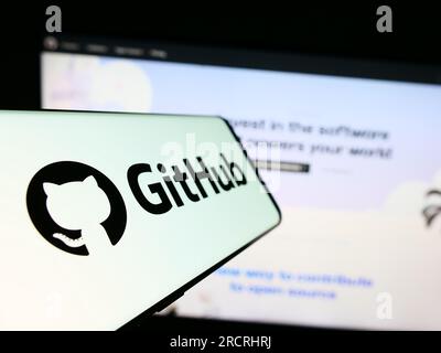 Cellphone with logo of American software development company GitHub Inc. on screen in front of website. Focus on center-left of phone display. Stock Photo