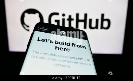 Mobile phone with webpage of US software development company GitHub Inc. on screen in front of business logo. Focus on top-left of phone display. Stock Photo