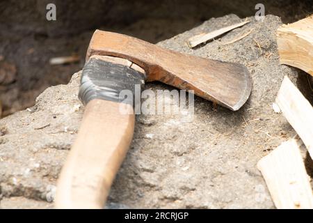 An old working ax lies on a granite stone in the summer in the forest while chopping firewood, a tool for chopping firewood, a lumberjack Stock Photo