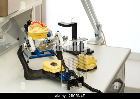 Articulator with plaster model of jaw stands on desktop of dental technician in  dental lab. Making dental crowns and prostheses Stock Photo