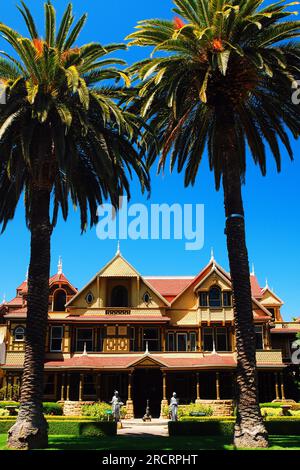 Two palm trees frame the Winchester Mystery House, historic and reportedly haunted home in San Jose, California Stock Photo