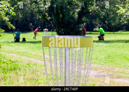 People playing flying disc golf sport game in the park or nature in the ...