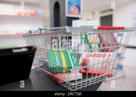 Pharmacy shopping basket filled with cardiology pills and vitamins packages standing on counter desk, waiting to customers to come and buy. Drugstore had a wide selection of medical products Stock Photo