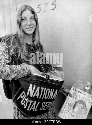 San Francisco, California:   November 12, 1975 A carrier for  the National Postal Service, a new competitor of the U.S. Post Office, delivers some magazines to a home in San Francisco. Stock Photo