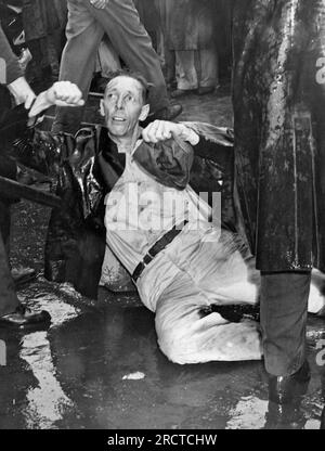 Los Angeles, California: October 1, 1946. An injured demonstrator at the MGM Studios lies on the pavement as a police officer holds him.. Many of the paraders are war veterans who have been locked out during the strike. Stock Photo