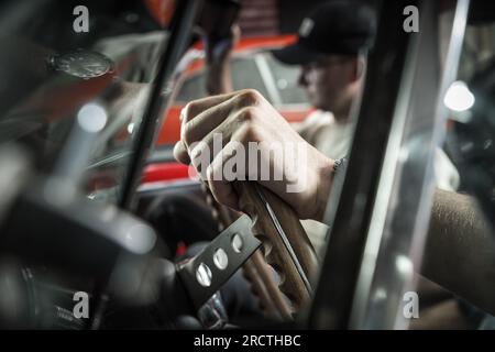 Two Guys Inside a Classic Car. Hand on Steering Wheel Close Up Stock Photo