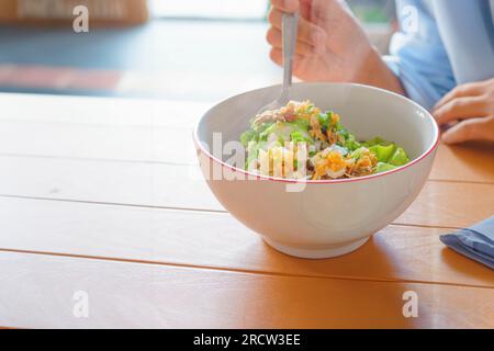 Girl Eating Bowl of Bubur ayam Bandung or Chicken Porridge, Indonesian traditional food consist of white rice porridge, shredded chicken Stock Photo