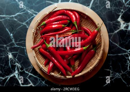 vintage bamboo rattan bowl with red spicy chili in background on table Stock Photo
