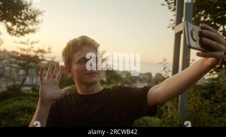 Handsome Blond Young Man Taking Selfies with His Smartphone, Striking Various Poses Outdoors Stock Photo