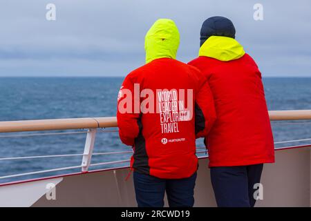 World Leader in Exploration Travel on back of Hurtigruten red jacket clothing on cruise ship at Greenland in July Stock Photo