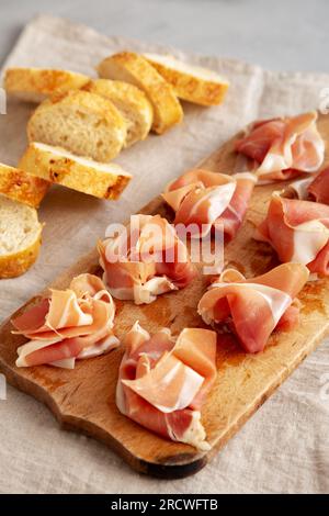 Slices of Appetizing Jamon Serrano Ready to Eat on a rustic wooden board, side view. Stock Photo