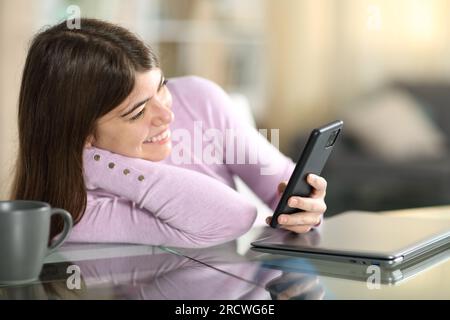 Happy teen watching content on phone sitting at home Stock Photo