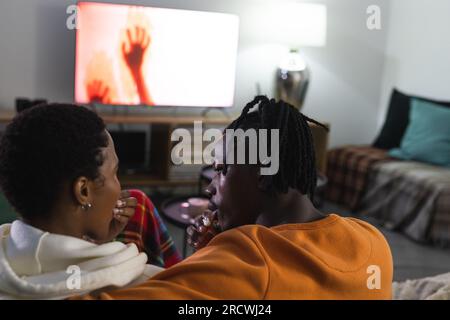 African american couple relaxing at home watching scary movie Stock Photo