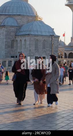Three friends walk in front of the Şemsi Pasha Mosque on a summers evening in Uskudar of the Asian side of Istanbul, Turkey Stock Photo