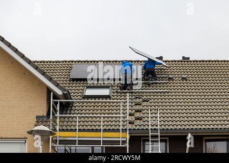 Barendrecht, the Netherlands - 2020-12-03: Two technicians installing photovoltaic panels on the roof of a home Stock Photo