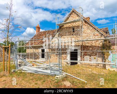 Scaffolding surrounding old country cottage house being renovated - Rosnay, Indre (36), France. Stock Photo