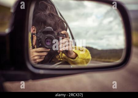 girl takes photo in car mirror Stock Photo